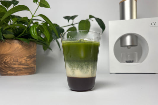 A glass of iced Earl Grey matcha latte with the Cuzen Matcha Maker in the background.