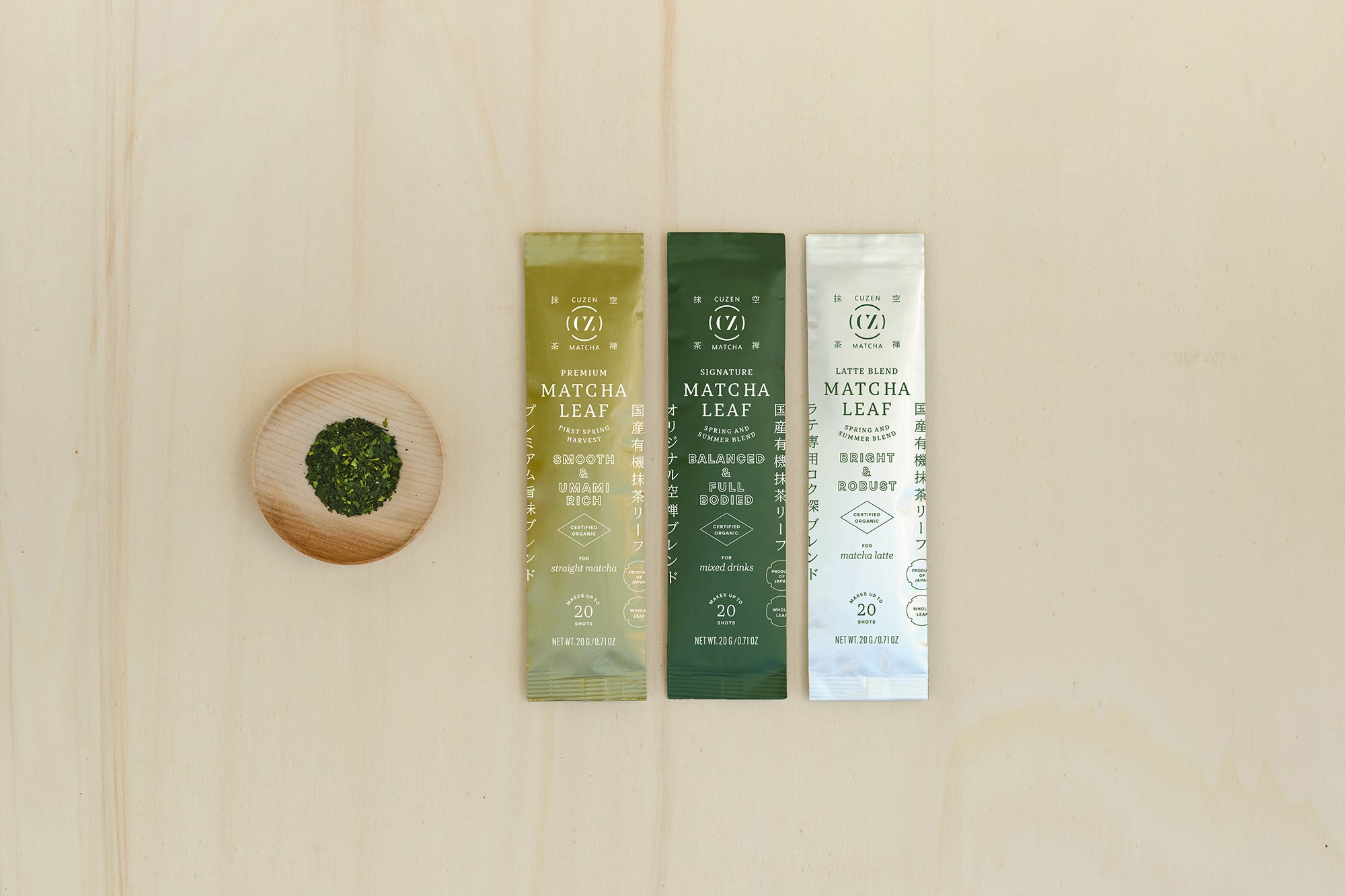 Cuzen’s three standard Matcha Leaf Blends in 20-gram packets, next to a saucerful of deep green, whole matcha leaves.