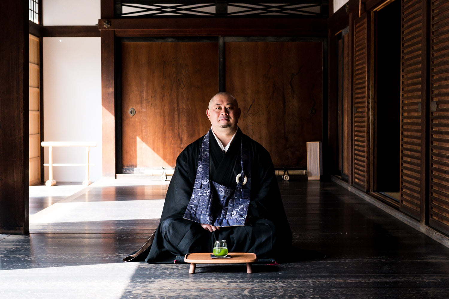 Shunkoin Temple’s Rev. Takafumi sitting in front of a sparkling matcha in an empty room with natural light.