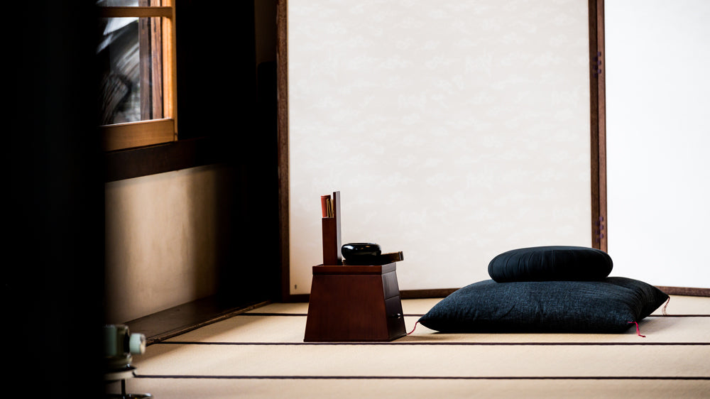 A box of incense and a black bowl, set on a small table between a window and a sitting pillow at Kyoto’s Shunkoin Temple.