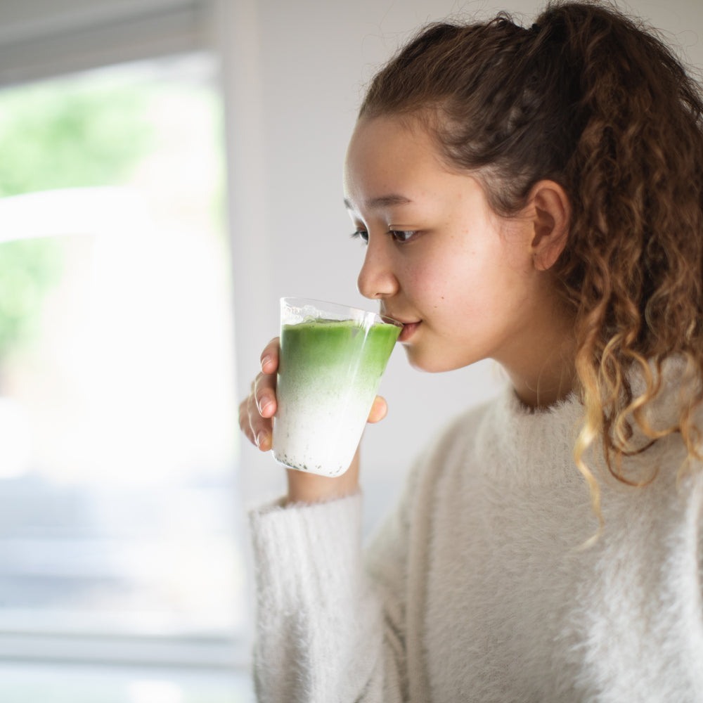 A woman sips a Perfect Matcha Latte Glass of creamy matcha latte.