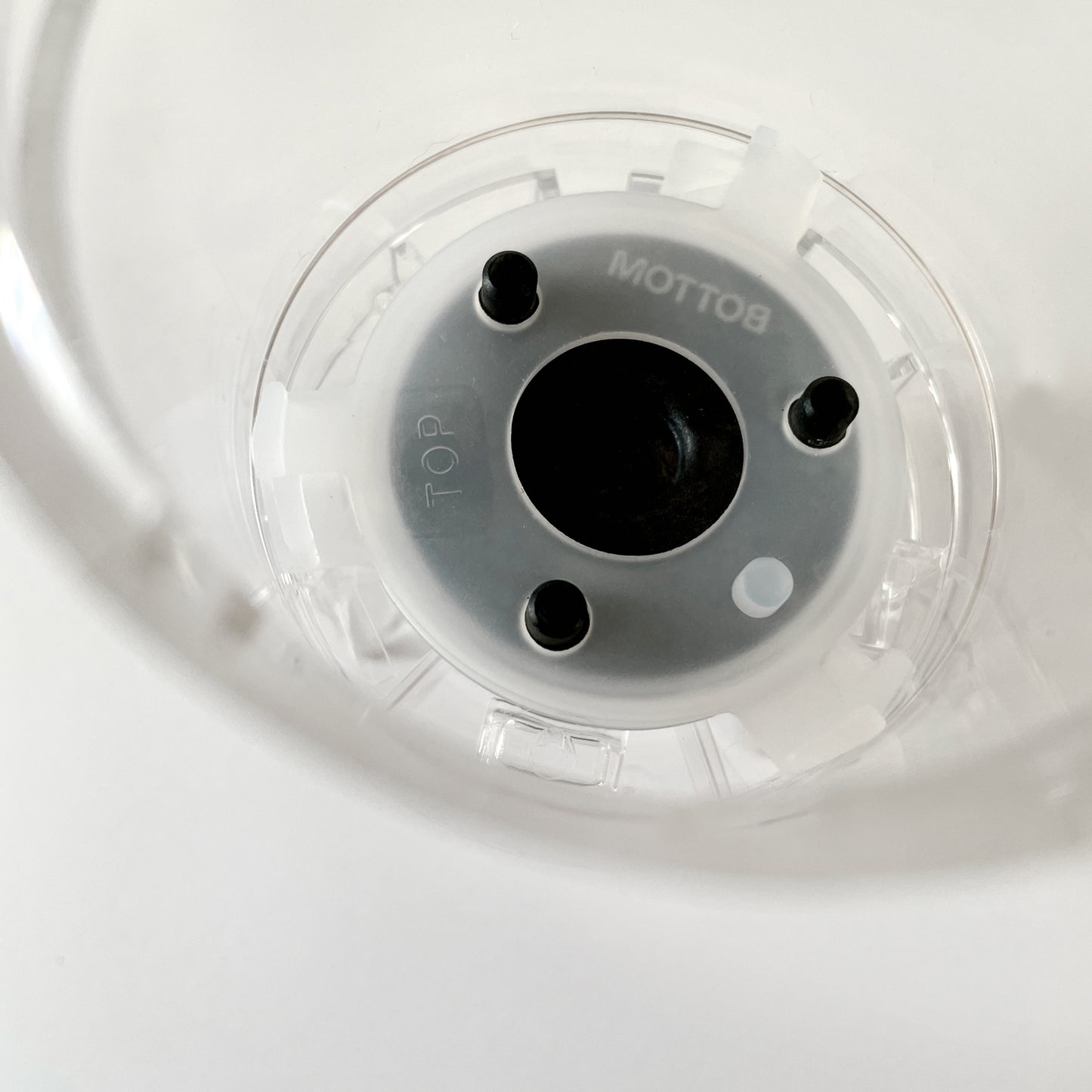 The lower spatula rests on three knobs in the lower part of the Cuzen Matcha Maker's ceramic mill unit.