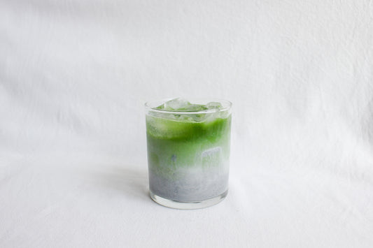 A matcha shot fading into a creamy-black sesame latte, over ice.