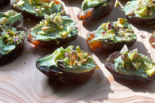 A group of soft deglet noor dates stuffed with bright green matcha cream cheese, sprinkled with pistachio bits.