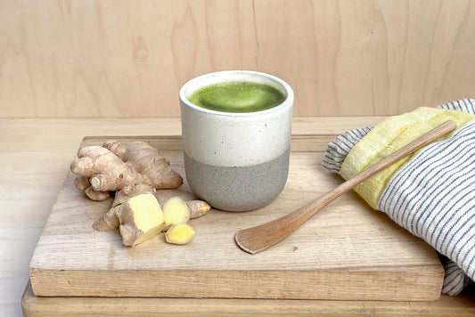 A warm ginger matcha latte in Cuzen’s Perfect Matcha Latte Cup with freshly chopped ginger root nearby.