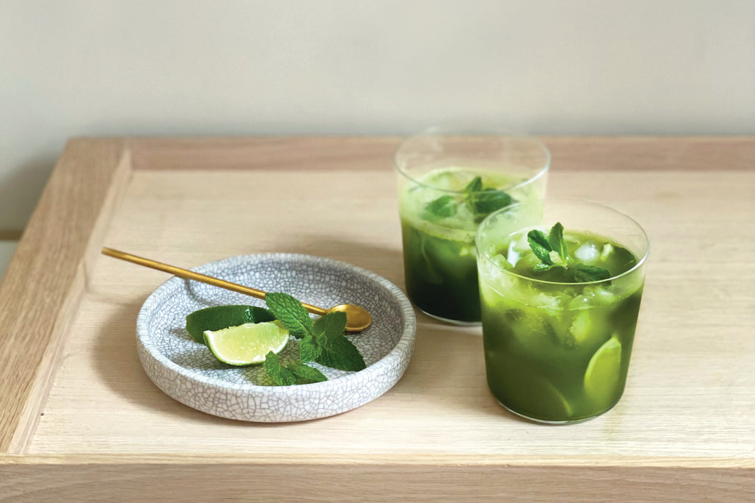 Two bright matcha-jitos garnished with mint and limes, bubbly and icy.