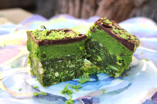 Two pieces nanaimo bars with layers of crunch, dark chocolate and bright green matcha.