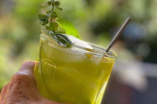 A frosty glass of mulled basil and matcha tonic, decked with a sprig of fresh basil