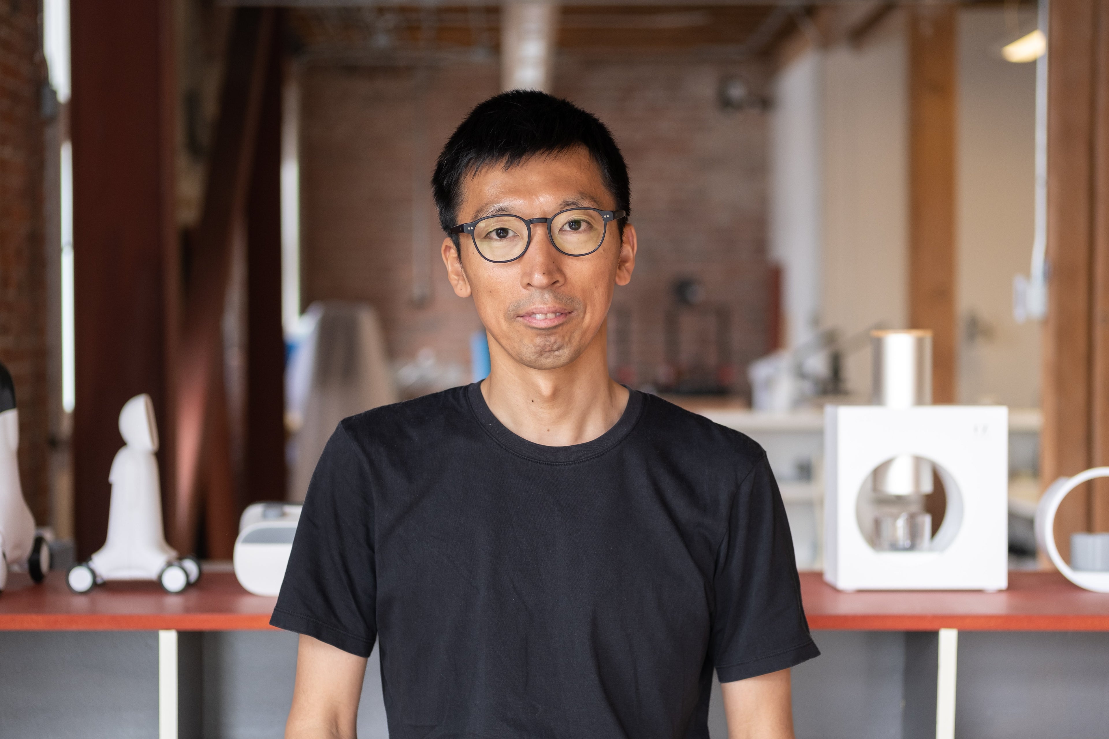 The product designer for Cuzen Matcha's Matcha Maker stands in front of his award-winning designs in his studio.