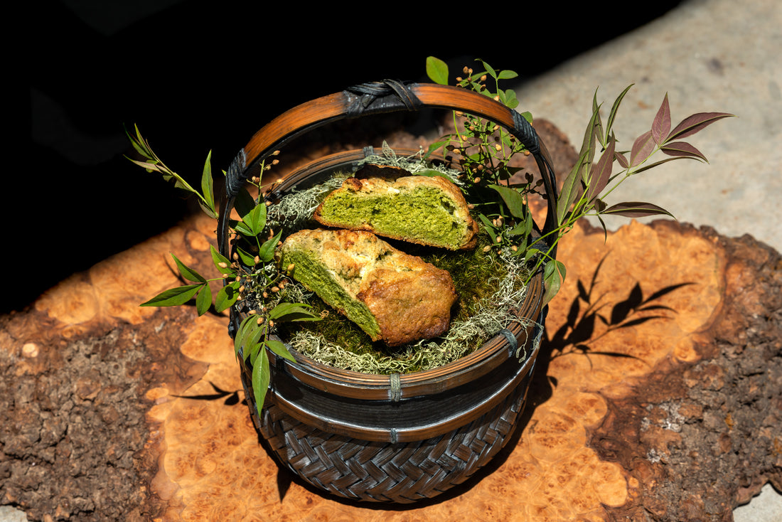 A halved matcha scone, bright green on the inside, sits inside a woven basket.