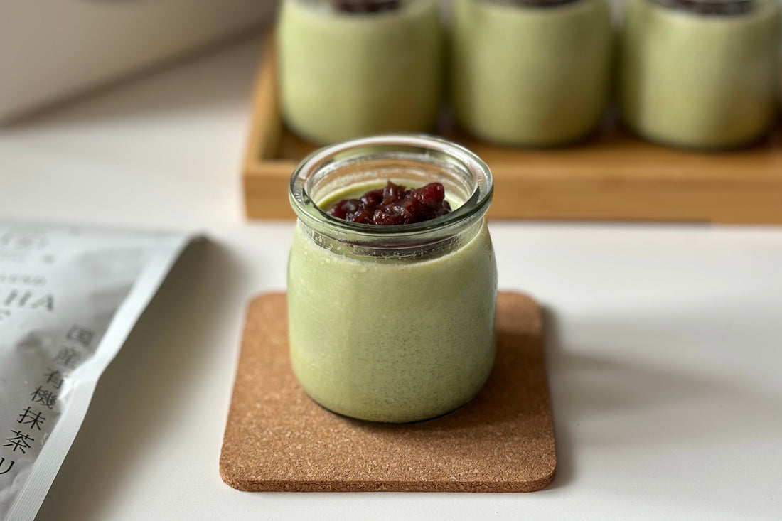 A small glass jar of matcha panna cotta, topped with sweet red beans.