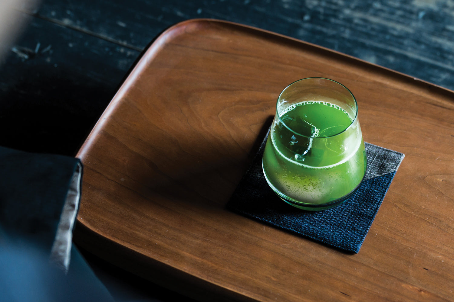 A glass of bright green, cold sparkling matcha on a tray.