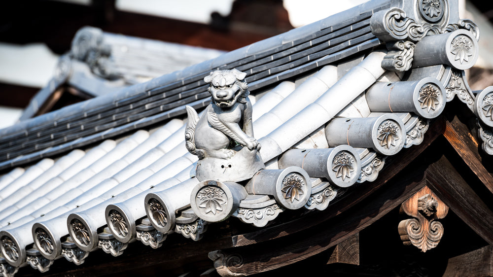 A small stone mythical guardian dog sits on the corner of a roof at Shunkoin Temple in Kyoto.