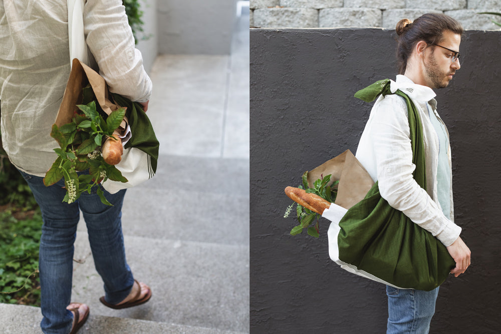 A person carries a baguette and fresh flowers in the furoshiki, which has been tied into a shopping bag.