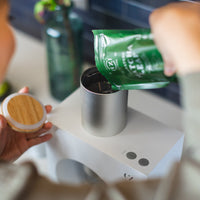 A person pours a packet of Cuzen’s Signature Blend Matcha Leaf into the Matcha Maker’s hopper.