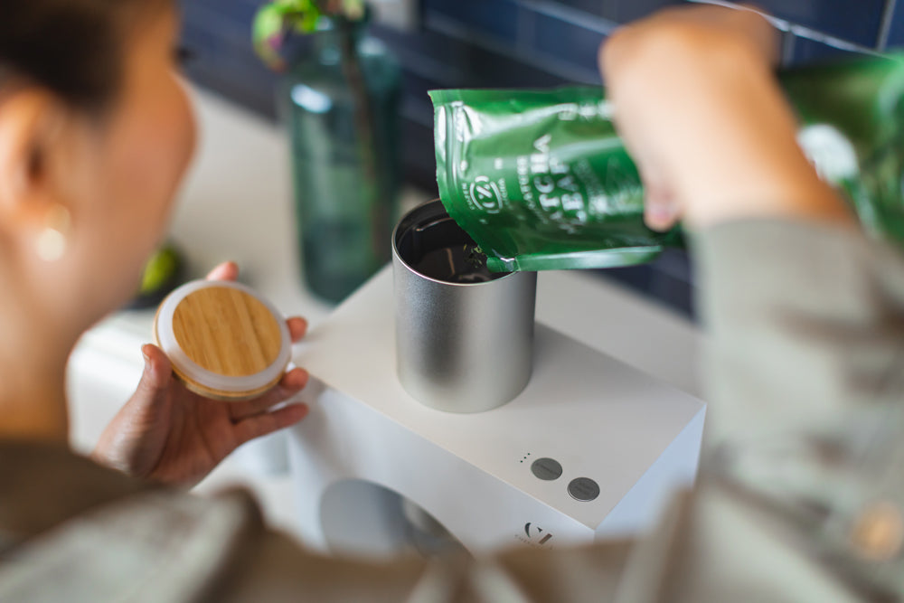A woman pours a packet of Signature Matcha Leaf into the Matcha Maker hopper.