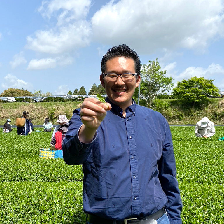 Cuzen founder, Eijiro Tsukada, smiles brightly as he shows a first harvest matcha leaf that he just plucked himself.