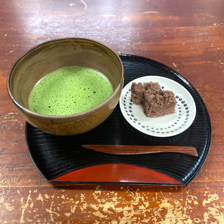 A large bright frothy bowl of matcha with an accompanying baked sweet.