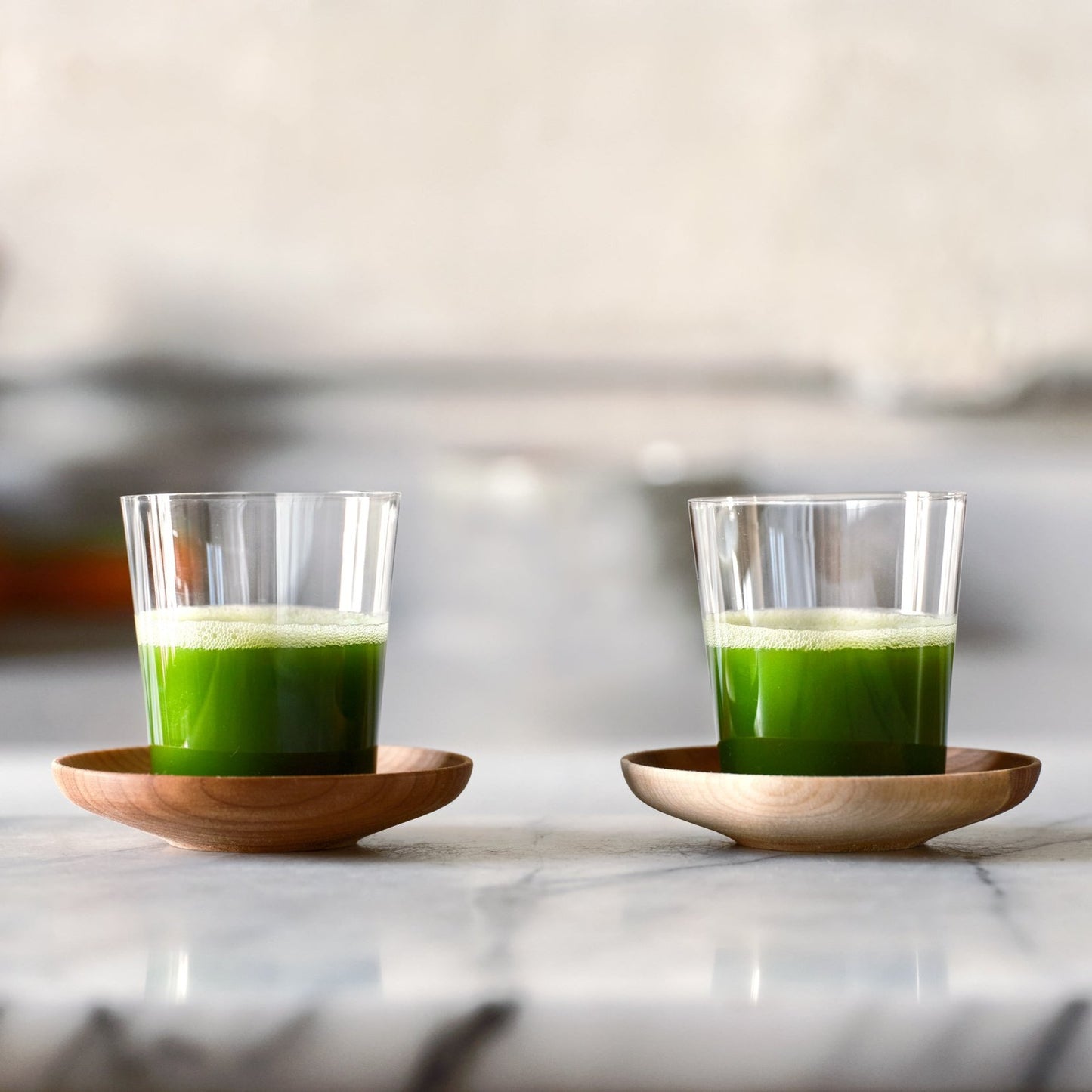 A pair of Matcha Shot Glasses and Wooden Saucers, full of vibrant green matcha shots.