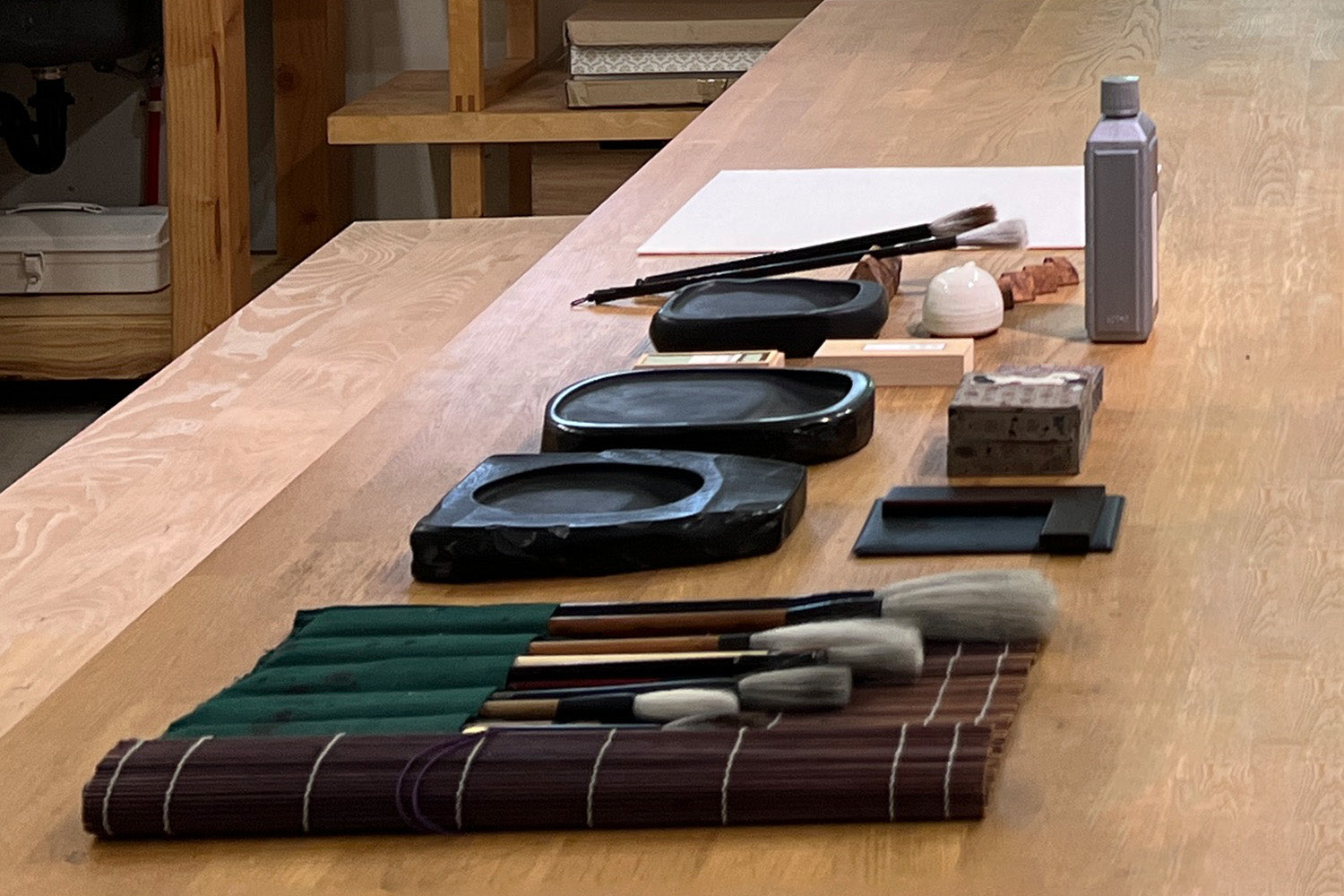 Fluffy brushes, ink pads and other calligraphy tools sit neatly-arranged on a work table in Aoi Yamaguchi’s studio.