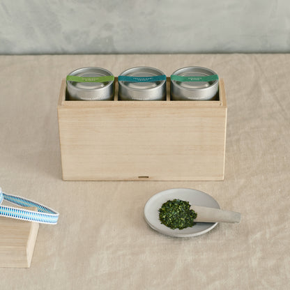 3 canisters of Single Origin Matcha Leaf in the kiri bako. A saucer with a mound of Matcha Leaf