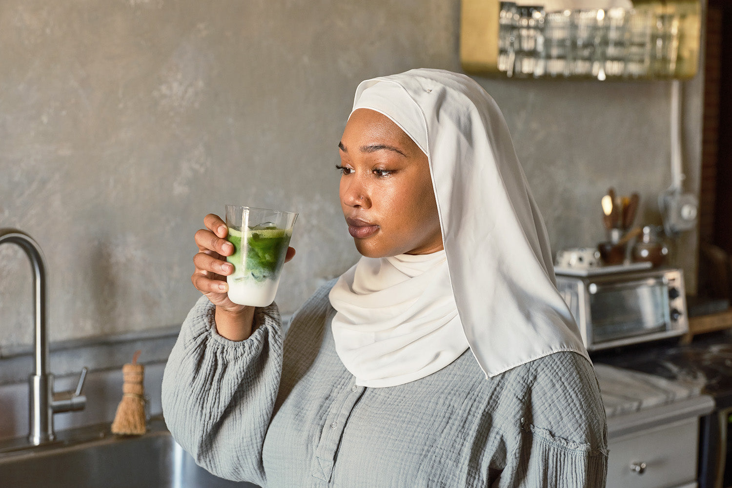 A woman pauses before taking a sip of an iced matcha latte in one of Cuzen's Perfect Matcha Latte Glasses.