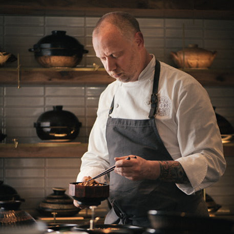 SingleThread owner and chef, Kyle Connaughton, prepares food in front of a wall of donabe pots.