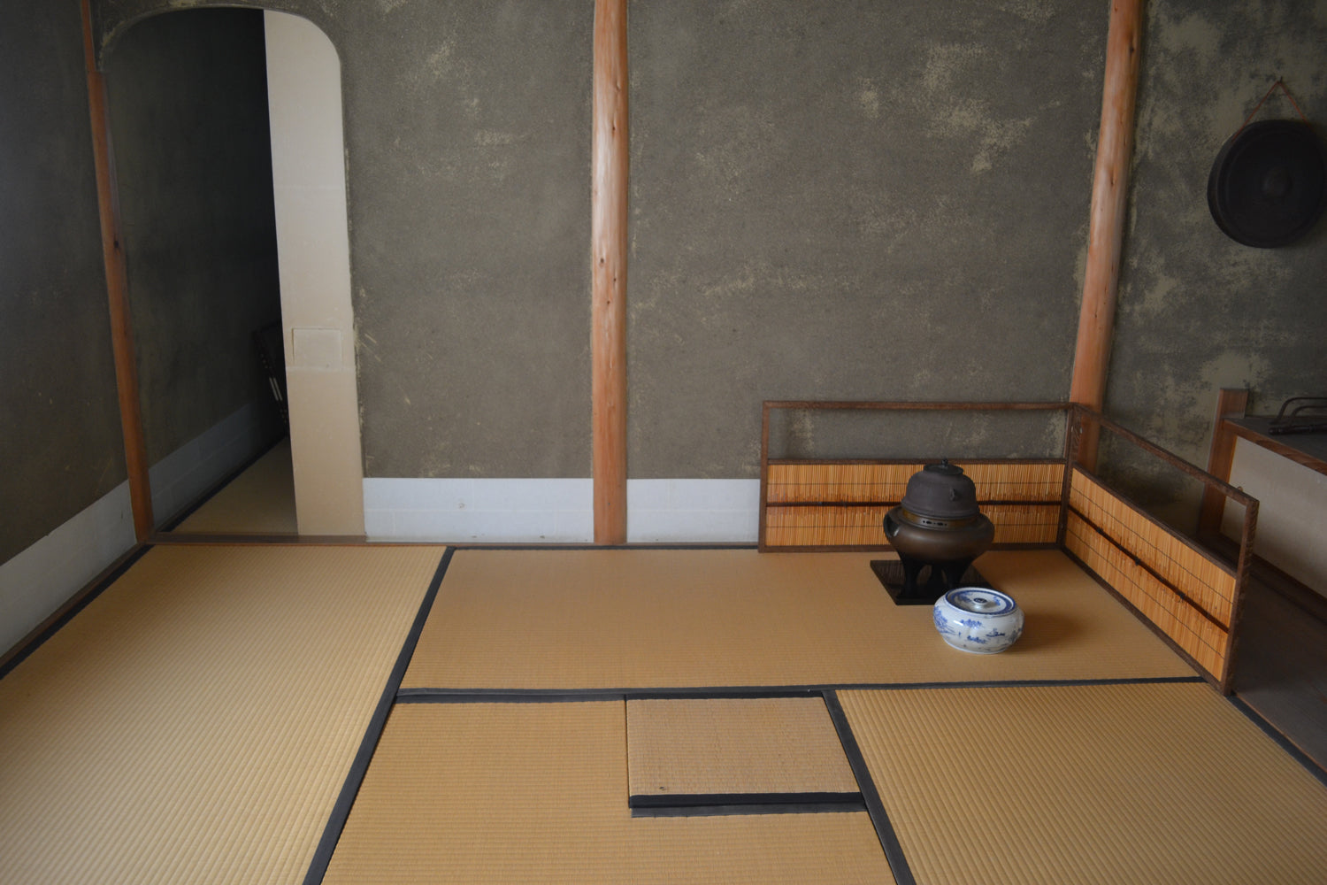 A simple, clean tea room with a “furo,” or portable brazier, and a “mizusashi,” or a “cold water container,” set in a corner, on a tatami mat.
