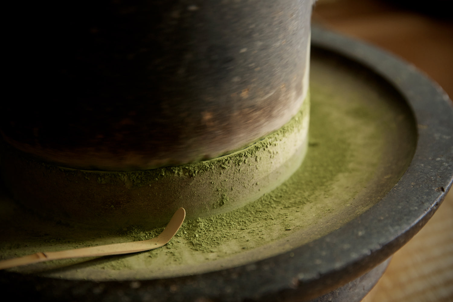 A “chashaku,” or “bamboo tea scoop,” set on a traditional stone mill covered in matcha powder.