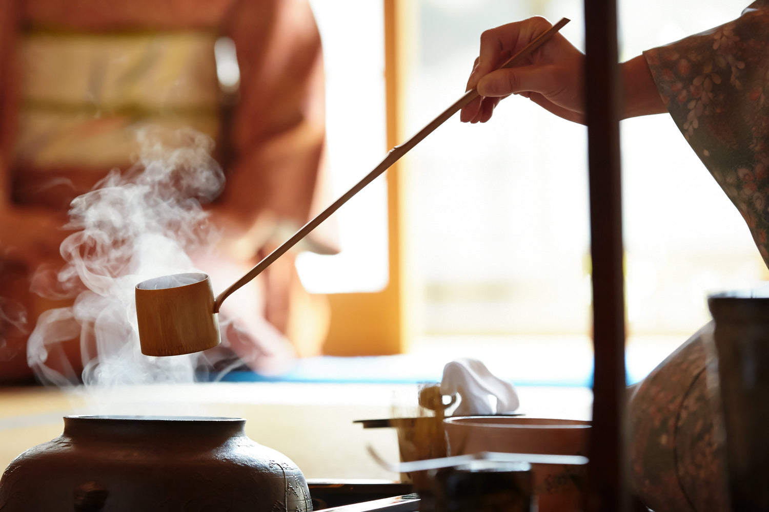A tea master holds a “hishaku,” or “bamboo ladle,” above a steaming pot during a tea ceremony.