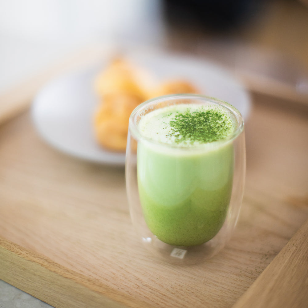 A glass of matcha latte, topped with a matcha powder dusting. 