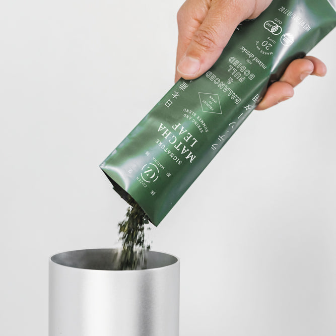 A hand pours a 20-gram packet of Signature Matcha Leaf into the Matcha Maker’s hopper.