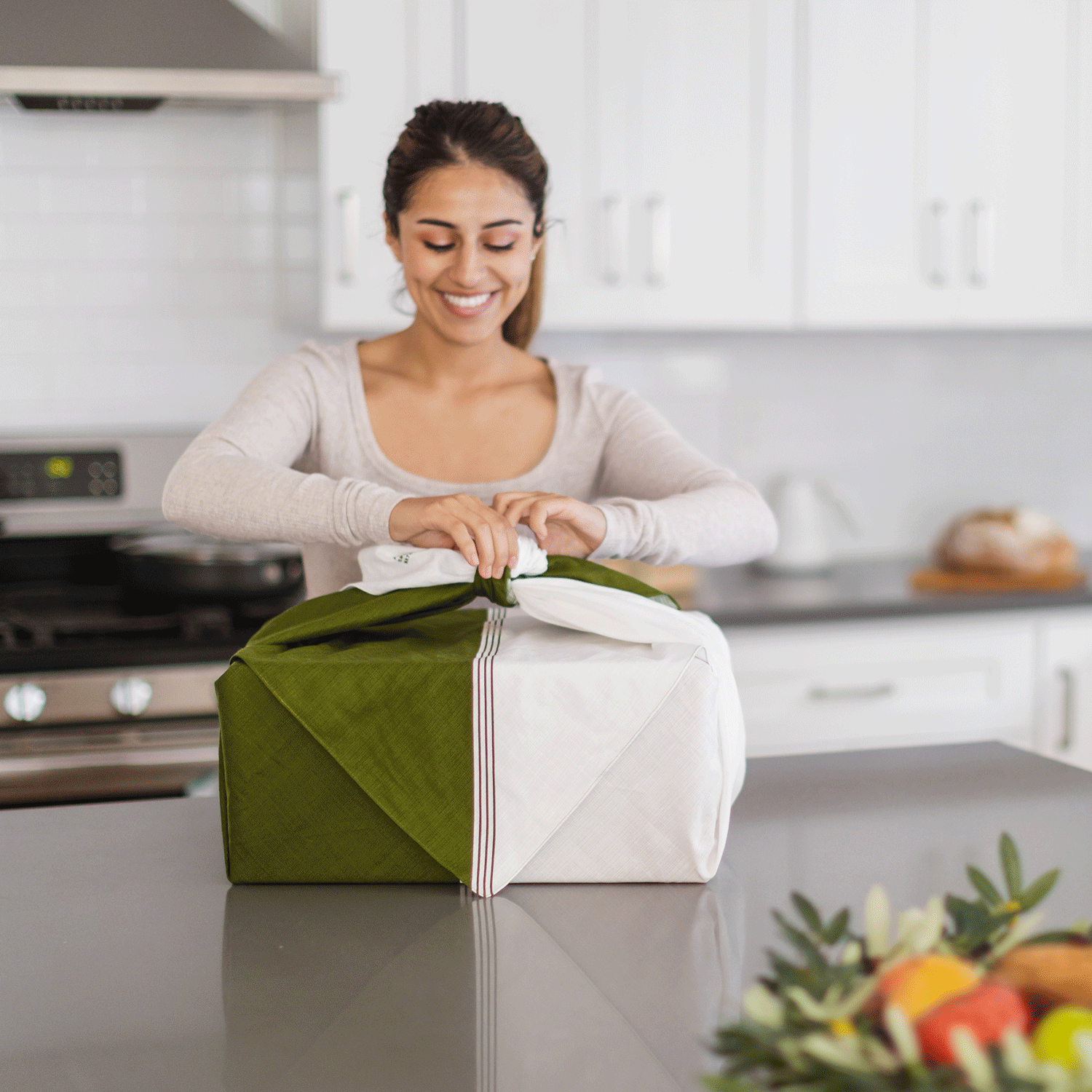 A smiling recipient of the Matcha Maker Gift Kit removes the furoshiki gift wrap and pulls out the machine.