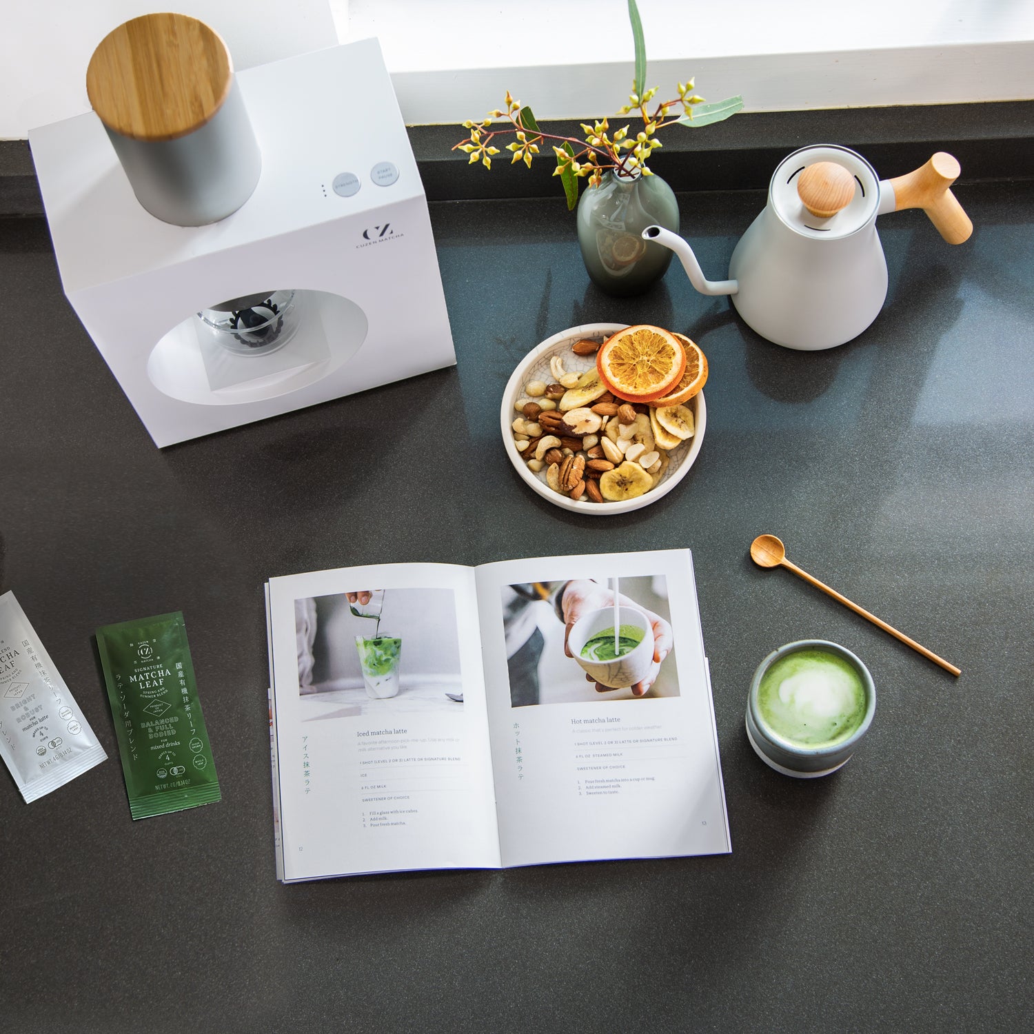 Cuzen Matcha | Matcha Maker, a booklet, leaf packets and matcha latte on kitchen counter